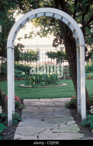 WEIßE HOLZ ARBOR FRAMES STEIN WEG IN MINNESOTA GARTEN.  BEGONIEN GRENZE WEG.  SOMMER. Stockfoto