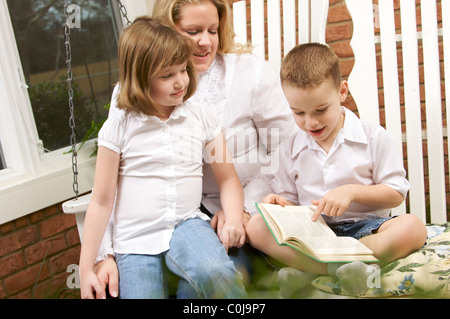 Liest der junge zu seiner Mutter und Schwester Stockfoto