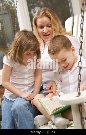 Liest der junge zu seiner Mutter und Schwester Stockfoto