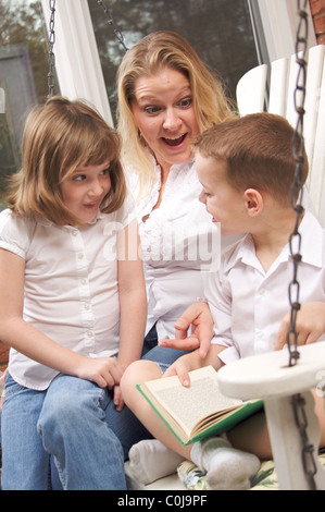 Liest der junge zu seiner Mutter und Schwester Stockfoto