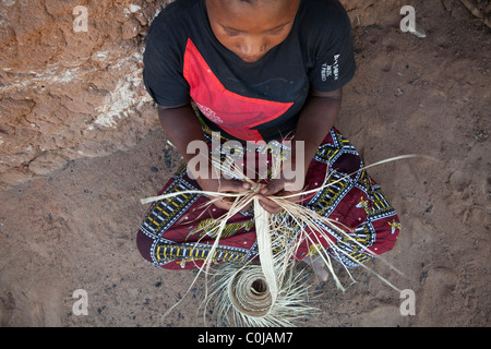 Eine erfahrene Frau spinnt einen Hut aus Stroh in Rufiji Bezirk, Tansania, Ostafrika. Stockfoto