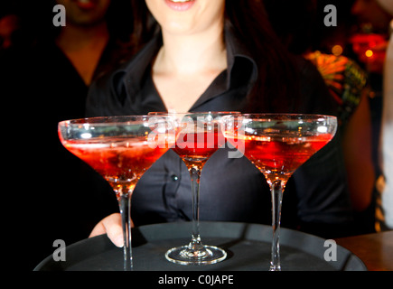 Eine Kellnerin hielt ein Tablett mit Rosa Champagner Gläser in einer bar Stockfoto