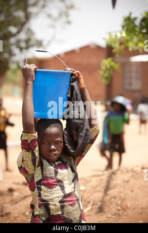 Ein Kind führt das Wasser wieder aus einem Brunnen in Dedza, Malawi, Südafrika. Stockfoto