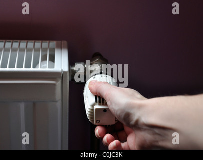 Person einstellen Thermostatregler auf eine Zentralheizung Stockfoto