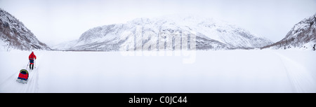 Ein Mann, der einen See überqueren, auf Skiern, Schlitten ziehen. Stockfoto