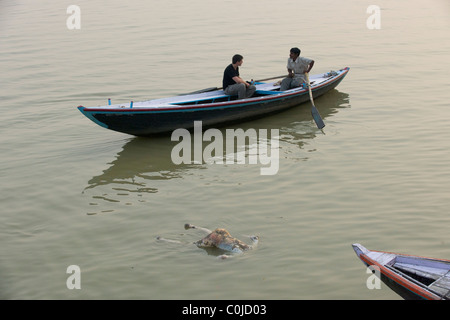 Körper einer toten Prgnant Frau schweben vorbei an westliche Tourist in einem Ruderboot auf dem Fluss Ganges, Varanasi, Uttar Pradesh, Indien Stockfoto