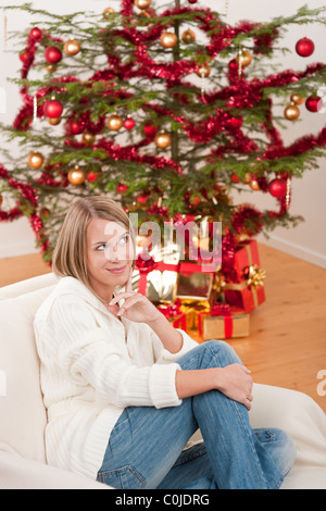 Glückliche junge Frau an Weihnachten vor Baum Stockfoto