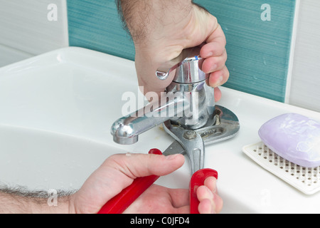 Nahaufnahme der Klempner Hände mit Schraubenschlüssel Zangen zu eng den Wasserablauf Stockfoto
