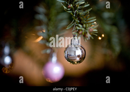 Eine silberne Christbaumkugel an einen Weihnachtsbaum hängen Stockfoto