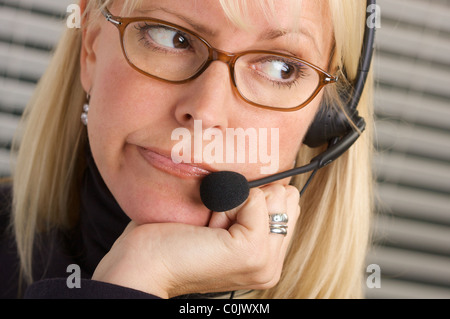 Gelangweilt Kundendienstberater Gespräche über ihr Handy Kopfhörer. Stockfoto