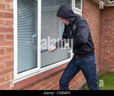 ein Mann versucht zu erzwingen, öffnen Sie ein Fenster auf einem Haus Stockfoto