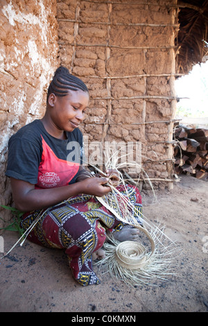 Eine erfahrene Frau spinnt einen Hut aus Stroh in Rufiji Bezirk, Tansania, Ostafrika. Stockfoto