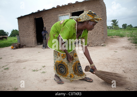 Eine junge Frau fegt die Familie Verbindung in ihrem Haus in Safo, Mali, Westafrika. Stockfoto