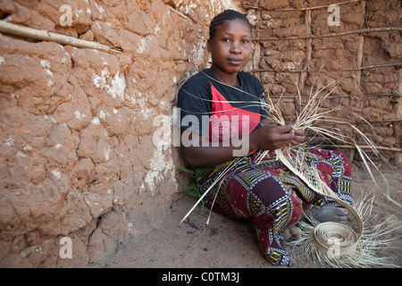 Eine erfahrene Frau spinnt einen Hut aus Stroh in Rufiji Bezirk, Tansania, Ostafrika. Stockfoto