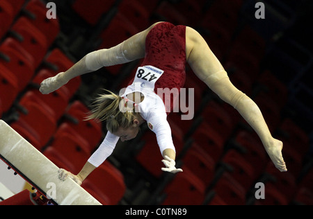 Weiblicher Gymnast führt einen Handstand mit nur einem Arm am Balken bei einem Gymnastik-Wettbewerb Stockfoto