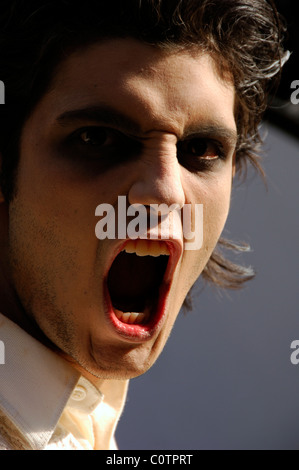 Gesicht eines jungen Mannes gekleidet wie ein Vampir oder ein Zombie mit offenem Mund Stockfoto