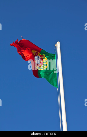 Portugiesische Fahnenschwingen auf einem Mast mit sonnigen blauen Himmel im Hintergrund Stockfoto