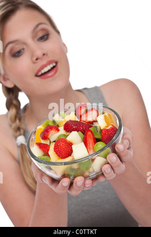 Gesunde Lebensweise Serie - Frau hält Schüssel Obstsalat auf weißem Hintergrund, Fokus auf Obst Stockfoto