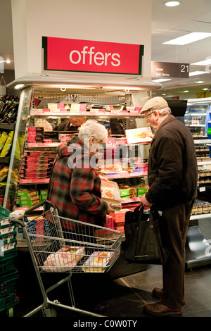 Ein altes, älteres Paar, das in der „Angebote“-Abteilung der Marks and Spencer Foodhall, Kent, Großbritannien, Lebensmittel einkauft Stockfoto