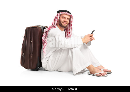 Arabische Mann sitzt in der Nähe einen Koffer und eine SMS auf sein Handy tippen Stockfoto