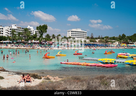 Greifen Sie auf Mittelmeer, Nissi Beach, Ayia Napa, Zypern.  Menschen am Strand und im Wasser, Hotels auf Hintergrund Stockfoto