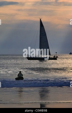 Surfer und Segelboot genießen Sie einen wunderschönen Sonnenuntergang im Oktober in Venice Beach, Kalifornien, USA. Stockfoto