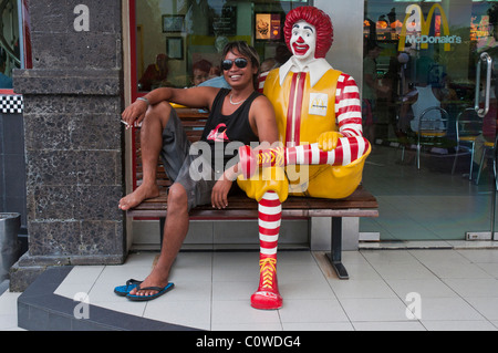 Eine balinesische Mann, sitzend mit dem Clown Ronald McDonald außerhalb der Sanur Beach-Filiale von McDonalds in Bali Indonesien Stockfoto