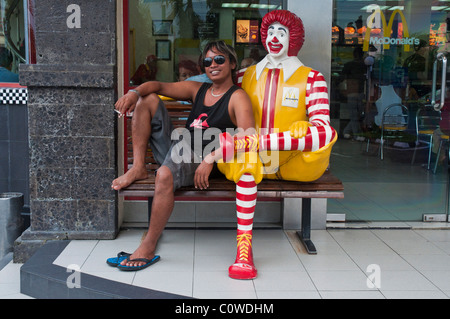 Eine balinesische Mann, sitzend mit dem Clown Ronald McDonald außerhalb der Sanur Beach-Filiale von McDonalds in Bali Indonesien Stockfoto