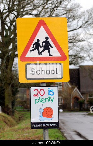 Schild am Straßenrand Schule und 20 km/h langsamer bitte Beschilderung auf einer Zufahrtsstraße zu einem Land Schule Hampshire UK Stockfoto