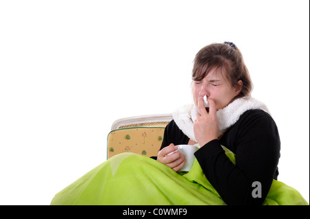 junge Frau unter grünen Decke setzen Nase Tropfen in ihre Nase. Isoliert auf weiss Stockfoto