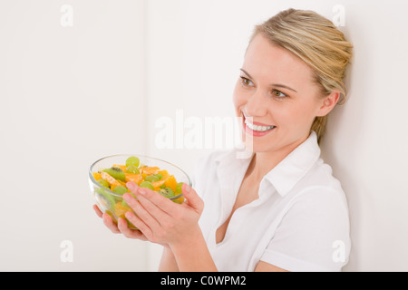 Gesunde Lebensweise - Frau Betrieb Schüssel mit Obstsalat auf weißem Hintergrund Stockfoto