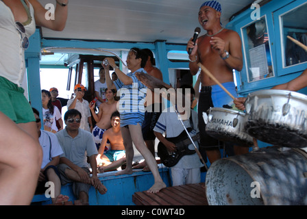 Touristen, die tanzen auf einem Boot während eines Tages Reise nach Nha Trangs vorgelagerten Inseln. Band spielt. Vietnamesen auf ein anderes Boot Stockfoto