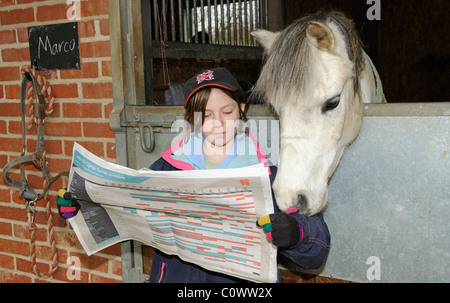 Kleines Mädchen mit einem London 2012 offizielle Olympia Mütze Blick durch den Spielplan mit ihrem Haustier pony Stockfoto