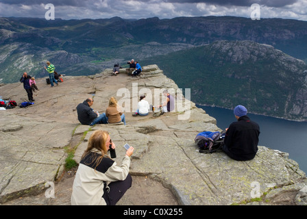 Leute sitzen auf dem Rand des Preikestolen Felsen in Norwegen Stockfoto