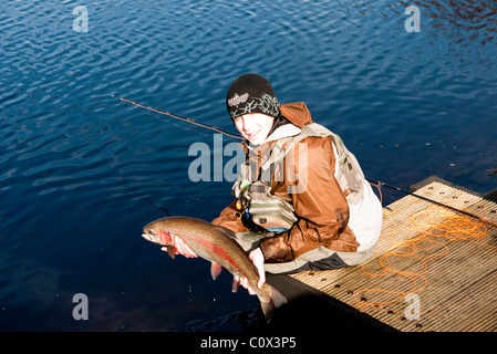 Junger Angler mit einer Regenbogenforelle (Oncorhynchus Mykiss), England UK. Stockfoto