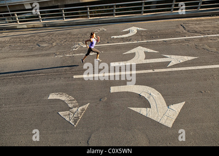 Weibliche Läufer laufen auf städtische Straße Brücke, Überführung mit Richtungspfeilen gemalt auf Bürgersteig Stockfoto