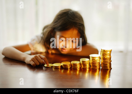 Investieren in Gold. Mädchen mit gestapelten Schokoladen gold-Münzen. Stockfoto