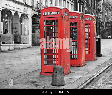 Drei rote Telefonzellen auf der Royal Mile in Edinburgh, Schottland, UK. Eine Frau sitzt in einem Café-Fenster. Stockfoto