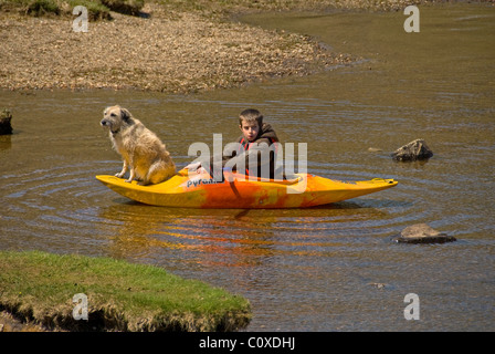 Junge im Kajak, Hund sitzt auf It, England, UK Stockfoto