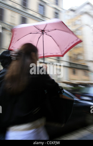 junge Frau mit Regenschirm bei starkem Regen in der Stadt Stockfoto