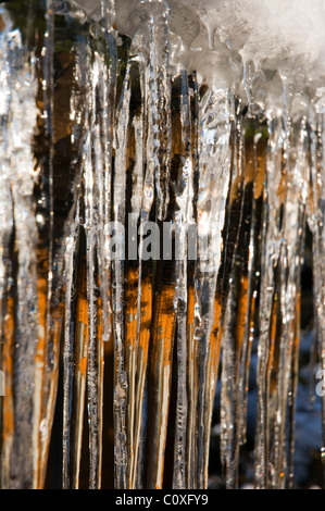 Eiszapfen hängen vom Dach eines hölzernen Gebäudes Stockfoto