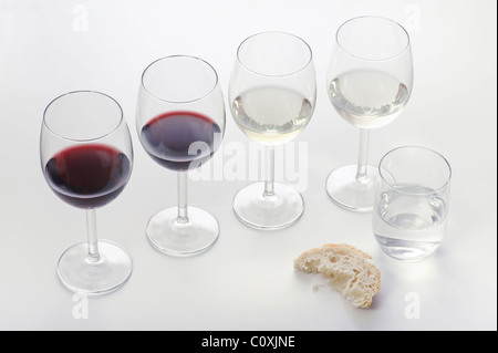 Vier Gläser Wein, rot und weiß, ein Glas Wasser und ein Stück Brot. Stockfoto