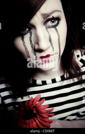 eine traurige weibliche MIME-Clown mit einer roten Blume Stockfoto