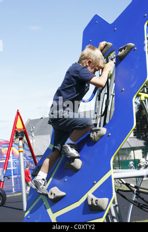 Kleiner Junge Klettern auf eine kleine Kletterwand in einen Kinderspielplatz Stockfoto