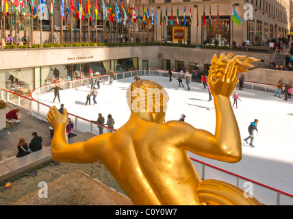 27. Februar 2011 - NYC: Gold-Statue von Prometheus von hinten mit Eisläufern, Menschenmengen, Flaggen am Rockefeller Center Staking Rink Stockfoto