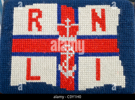 RNLI-Logo in Handarbeit auf eine Kirche Grasbüschel. Stockfoto