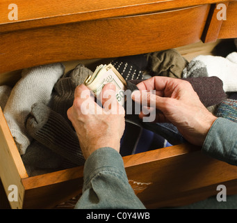 Mann versteckt Bargeld in Socken-Schublade Stockfoto
