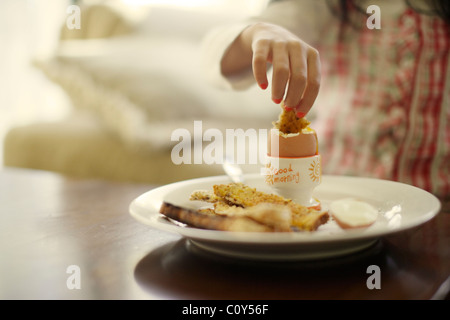 Mädchen isst gekochtes Ei mit Toast Soldaten zum Frühstück Stockfoto