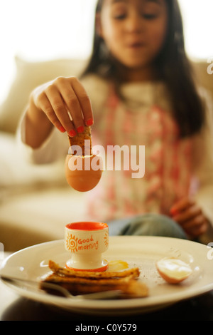 Mädchen isst gekochtes Ei mit Toast Soldaten zum Frühstück Stockfoto