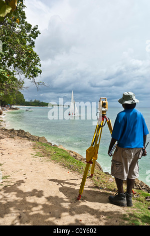 Jung engineering Landvermesser verwendet ein Theodolit an einem Strand von Barbados Stockfoto